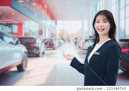 一名年輕女子在汽車經銷店為顧客服務 一名年輕女子在汽車經銷店為顧客服務 123344743