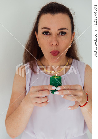 Beautiful brunette woman blowing out a green candle Beautiful brunette woman blowing out a green candle 123344972