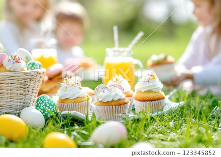Children enjoying a spring picnic with cupcakes and juice in a sunny garden setting 123345852