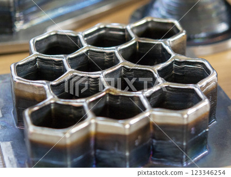 Objects printed with a 3D printer from a filament of molten metal on a table. Objects printed with a 3D printer from a filament of molten metal on a table. 123346254