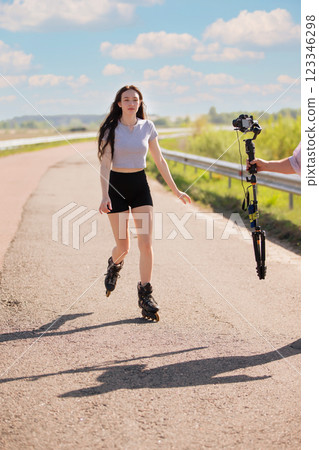 A woman rollerblades on the road and is filmed. 123346298