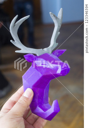Person holding in hand an art object printed on 3D printer. Abstract toy model purple deer with gray horns created on 3d printer. FDM. Concept 3D Printing. Additive modern new progressive technologies Person holding in hand an art object printed on 3D printer. Abstract toy model purple deer with gray horns created on 3d printer. FDM. Concept 3D Printing. Additive modern new progressive technologies 123346394
