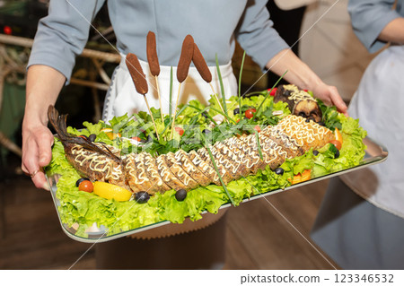 The dish from the restaurant is stuffed pike decorated with lettuce leaves and reeds. Expensive food from the chef. 123346532