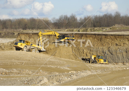 Yellow dump trucks and excavator are working in gravel pit Yellow dump trucks and excavator are working in gravel pit 123346679