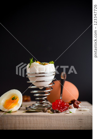 red caviar in a spoon and morning boiled egg for breakfast, isolated on black background red caviar in a spoon and morning boiled egg for breakfast, isolated on black background 123347726