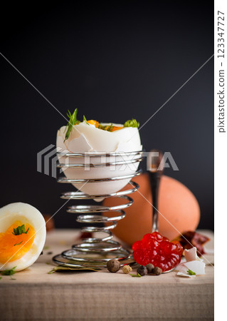 red caviar in a spoon and morning boiled egg for breakfast, isolated on black background red caviar in a spoon and morning boiled egg for breakfast, isolated on black background 123347727