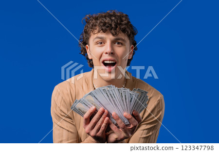 Rich Man With Usd Currency. Young American Guy Holding Money On Blue,Won Lottery Rich Man With Usd Currency. Young American Guy Holding Money On Blue,Won Lottery 123347798