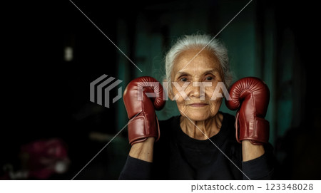 Portrait of old woman wearing boxing gloves in gym, commitment to active lifestyle of seniors, copy space for wellness and fitness lifestyle concept for retired seniors 123348028