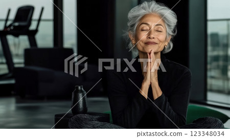 Senior woman meditating after workout in gym, commitment to active lifestyle for seniors, copy space for wellness and fitness lifestyle concept for seniors in retirement 123348034