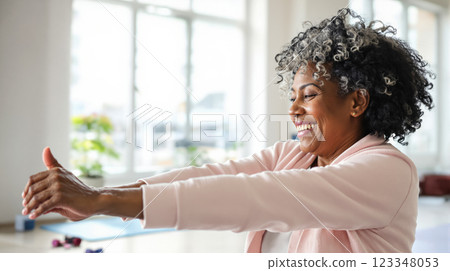 Happy elderly lady enjoying exercise in fitness room in bright morning sun in gym, copy space for health and exercise concept for seniors 123348053