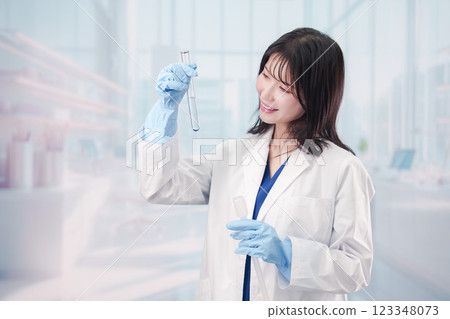 A female researcher in a white coat conducting an experiment A female researcher in a white coat conducting an experiment 123348073