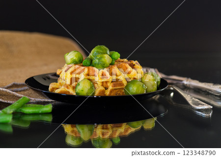 Vegetarian waffles with vegetables on a black plate, isolated on a black background Vegetarian waffles with vegetables on a black plate, isolated on a black background 123348790
