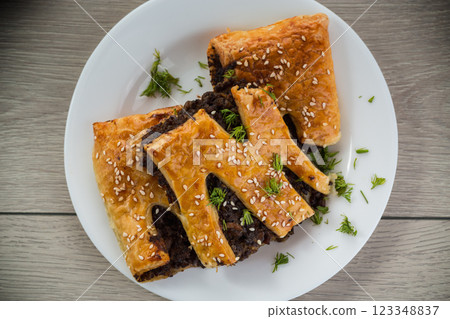 Golden puff pastries with mushroom filling and sesame seeds, on a light wooden table Golden puff pastries with mushroom filling and sesame seeds, on a light wooden table 123348837