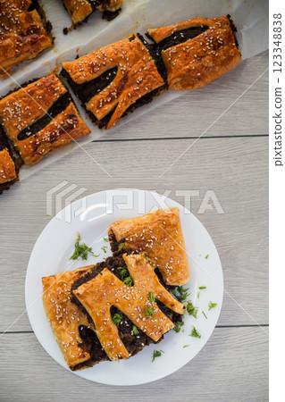 Golden puff pastries with mushroom filling and sesame seeds, on a light wooden table 123348838