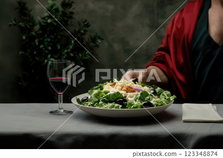Caesar salad and a glass of red wine on the table in a cafe, modern Mediterranean cuisine and wine traditions, concept of keto diet and fresh products for salads 123348874