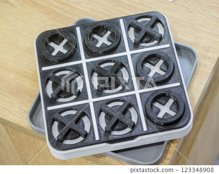 Model of the toy Tic-tac-toe printed on 3D printer close-up. Object created on 3D printer from molten plastic of black and white color. 3D printing technology. Additive modern progressive technologies Model of the toy Tic-tac-toe printed on 3D printer close-up. Object created on 3D printer from molten plastic of black and white color. 3D printing technology. Additive modern progressive technologies 123348908
