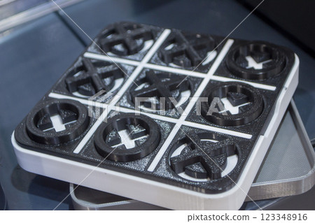 Model of the toy Tic-tac-toe printed on 3D printer close-up. Object created on 3D printer from molten plastic of black and white color. 3D printing technology. Additive modern progressive technologies Model of the toy Tic-tac-toe printed on 3D printer close-up. Object created on 3D printer from molten plastic of black and white color. 3D printing technology. Additive modern progressive technologies 123348916