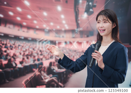 A young woman hosting a concert in a hall with a large audience 123349100