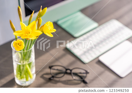 Modern light working space for office or home with green computer, keyboard, glasses and daffodils on the table Modern light working space for office or home with green computer, keyboard, glasses and daffodils on the table 123349250