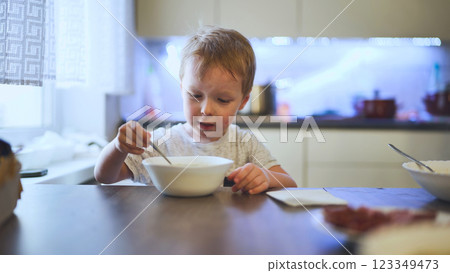 Blond toddler eating a bowl of hot soup on a cold winter day at home, enjoying a warm meal 123349473