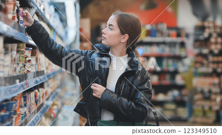 Young woman selecting grocery items, browsing shelves, purchasing fresh produce Young woman selecting grocery items, browsing shelves, purchasing fresh produce 123349510