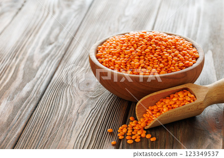 Red lentils are overflowing a wooden bowl and scoop, creating warm and inviting scene on a rustic table Red lentils are overflowing a wooden bowl and scoop, creating warm and inviting scene on a rustic table 123349537
