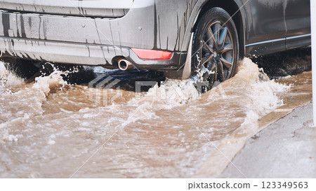 Muddy vehicle splashing through roadside puddle during wet, overcast weather conditions Muddy vehicle splashing through roadside puddle during wet, overcast weather conditions 123349563