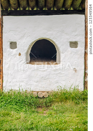 Whitewashed outdoor stove with wooden roofing in a grassy area, showcasing traditional russian construction Whitewashed outdoor stove with wooden roofing in a grassy area, showcasing traditional russian construction 123349564