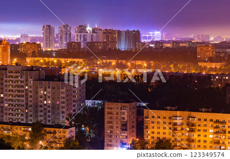Warm residential buildings glowing against luminous urban skyline, creating dramatic contrast under dimming evening light 123349574