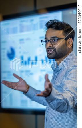 Professional speaker giving business presentation with graphs and charts, discussing data analysis in corporate environment Professional speaker giving business presentation with graphs and charts, discussing data analysis in corporate environment 123349645