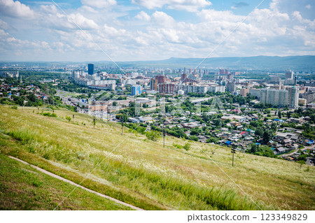 Panoramic view of krasnoyarsk, russia, showcasing the cityscape with green hills in the foreground and a cloudy blue sky. 123349829