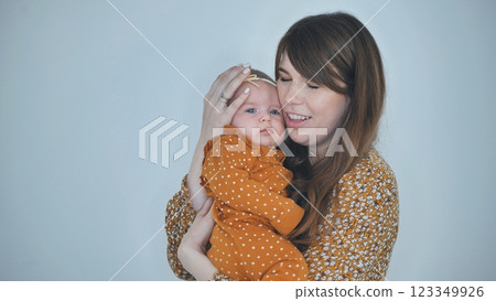 Nurturing mother embracing newborn daughter, sharing intimate bond within soft lit professional photography studio 123349926