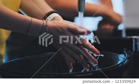 Woman carefully washing her hands with soap and water in a basin, promoting hygiene and cleanliness 123350024