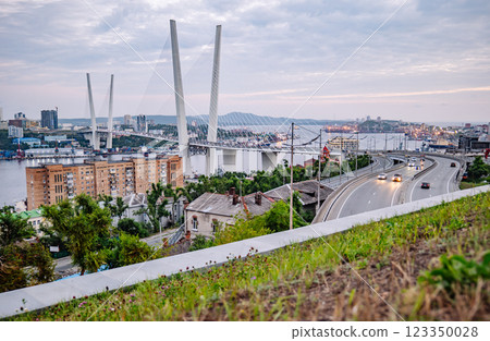 Golden cable stayed bridge spanning zolotoy rog bay, illuminated roadway carrying traffic during twilight hours in vladivostok, russia Golden cable stayed bridge spanning zolotoy rog bay, illuminated roadway carrying traffic during twilight hours in vladivostok, russia 123350028