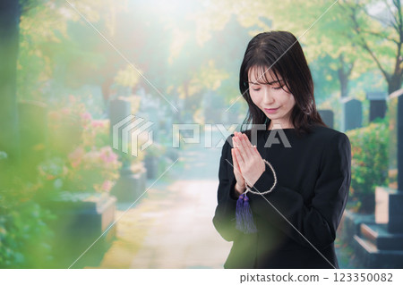 A woman in mourning clothes visiting a grave A woman in mourning clothes visiting a grave 123350082