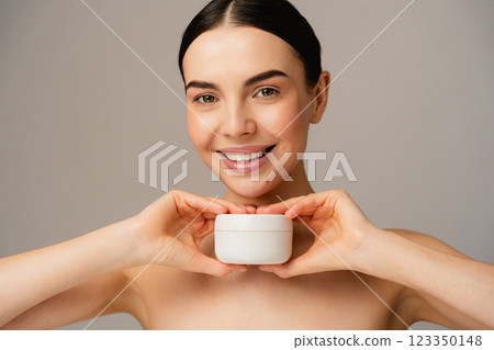 Smiling Woman Holding Skin Care Cream Jar in a Studio Setting 123350148
