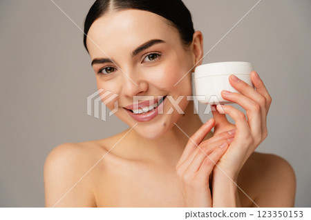 Smiling Woman Holding White Cream Jar Promoting Cosmetics and Skincare Products 123350153