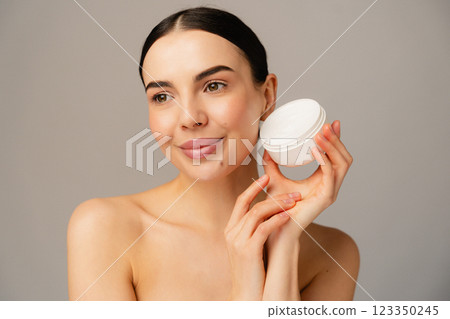 Smiling Woman Holding Skincare Product in Hands on Neutral Background Smiling Woman Holding Skincare Product in Hands on Neutral Background 123350245