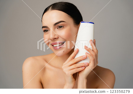 Smiling Woman Holding Shampoo Bottle Promoting Skincare and Beauty Products 123350279