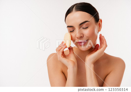 Relaxed Woman Skincare Routine with Gentle Face Cleansing Sponge on White Background Relaxed Woman Skincare Routine with Gentle Face Cleansing Sponge on White Background 123350314