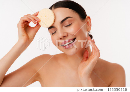 Smiling Woman Enjoying Skincare Routine With Cleansing Sponge Smiling Woman Enjoying Skincare Routine With Cleansing Sponge 123350316