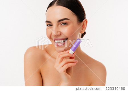 Smiling Bare-Skinned Model Holding a Purple Lip Balm Against White Background 123350468