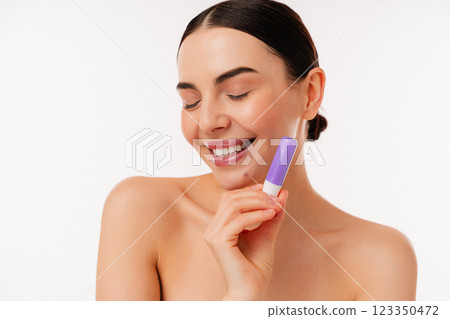 Smiling Woman Holding Purple Product Against a White Background Smiling Woman Holding Purple Product Against a White Background 123350472