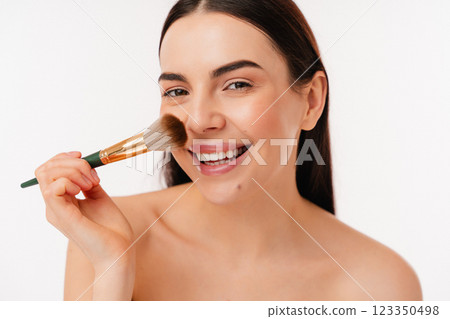 Smiling Woman Applying Makeup with Brush on White Background Smiling Woman Applying Makeup with Brush on White Background 123350498