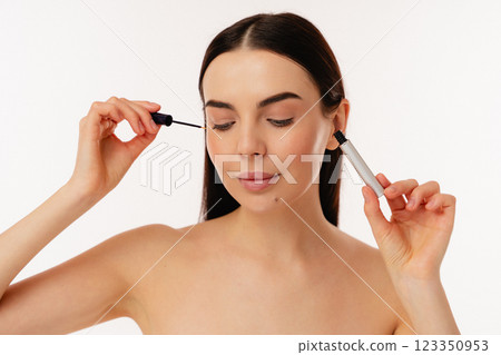 Person Applying Makeup With Mascara Wand on a Bright Background Person Applying Makeup With Mascara Wand on a Bright Background 123350953