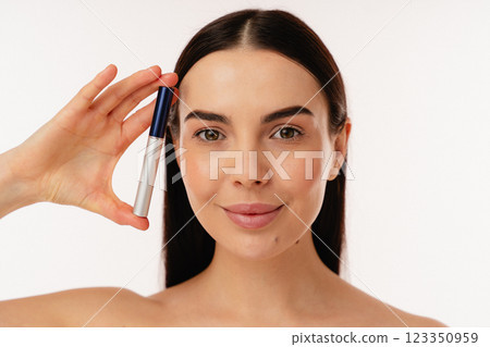 Smiling Woman Holding Cosmetic Product With a Clean White Background Smiling Woman Holding Cosmetic Product With a Clean White Background 123350959