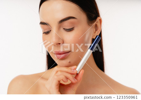 Young Woman Holding a Cosmetic Tube with a Neutral Expression 123350961