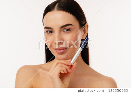 Smiling Woman Holding Makeup Product on White Background in Studio 123350963