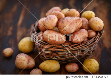 Raw fresh potatoes in the basket on wooden background Raw fresh potatoes in the basket on wooden background 123350974