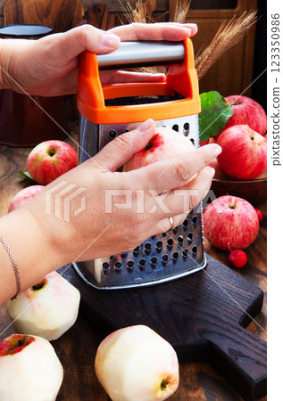 Women's hands grate apples for making apple pie 123350986